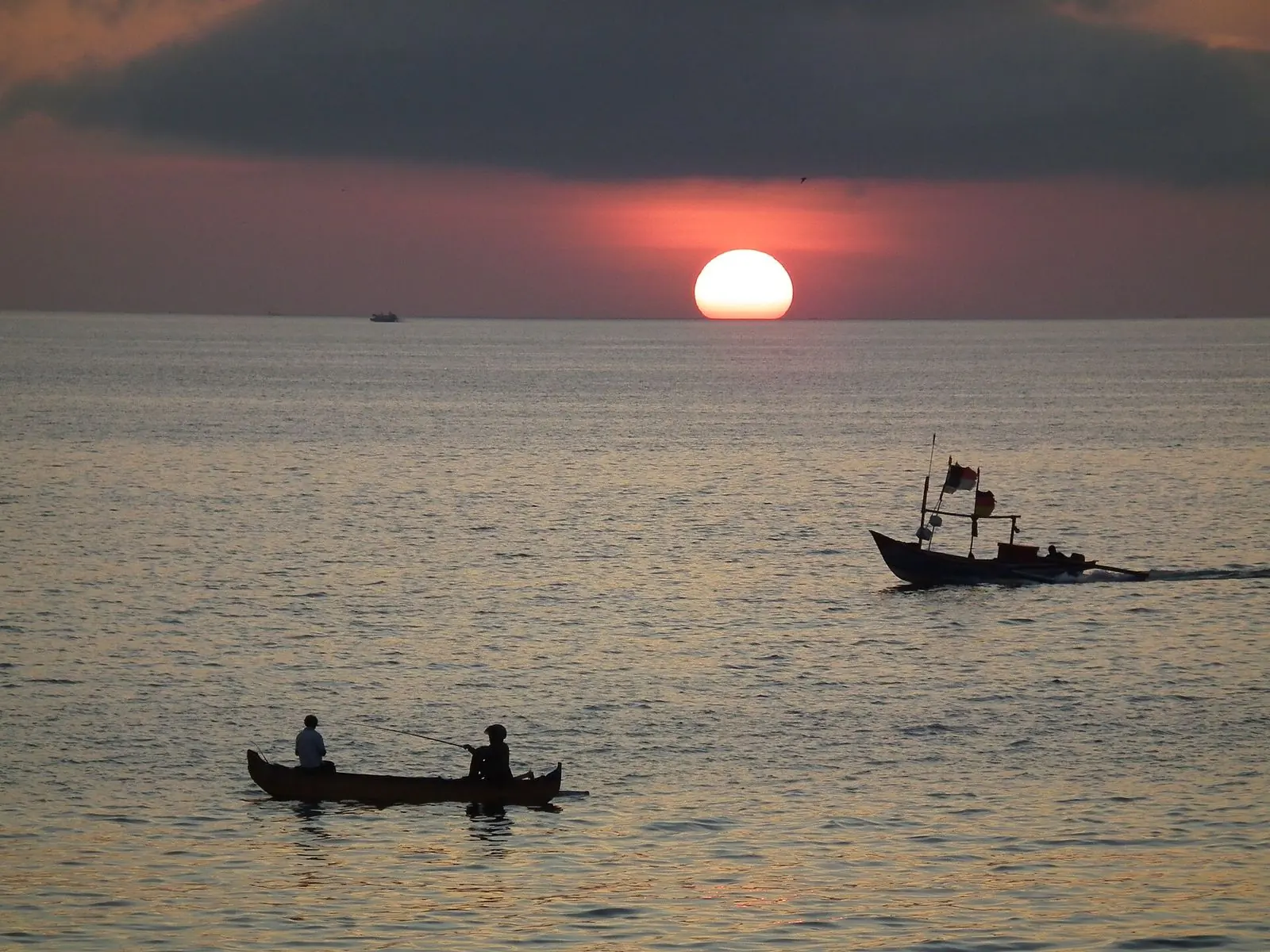 Matahari terbenam di Teluk Jimbaran dengan perahu-perahu nelayan